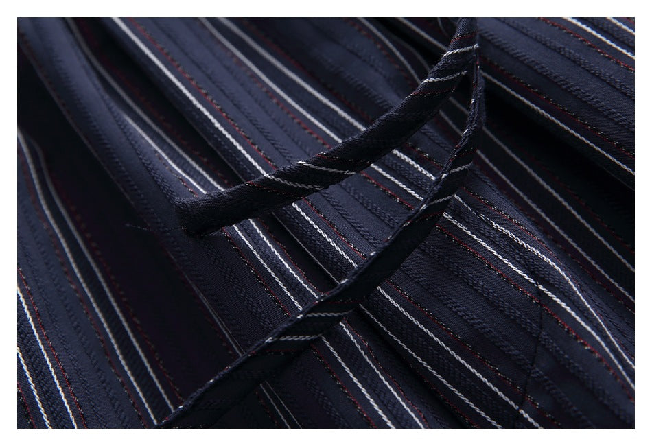 Close-up of a dark drawstring against dark navy fabric with fine white and muted red stripes.