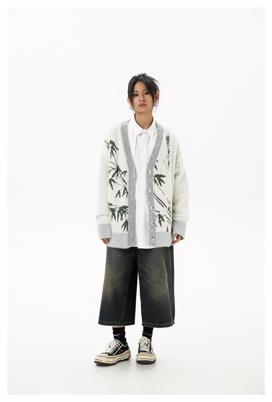 Model wearing beige bamboo-pattern cardigan open over a white shirt with wide denim shorts and sneakers