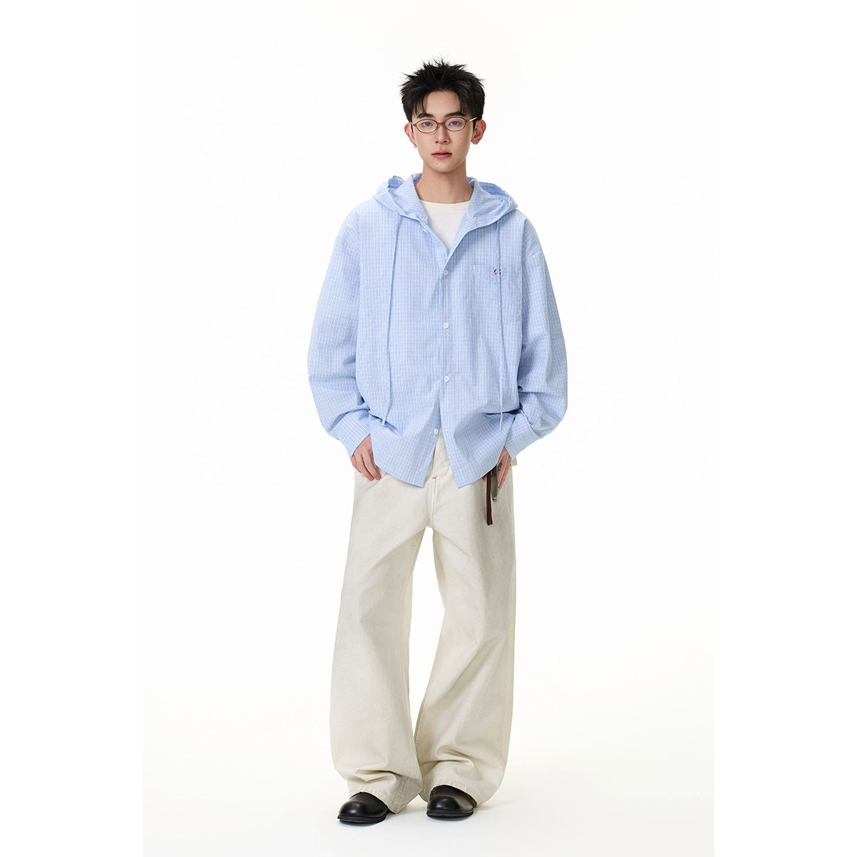 Full-length view of a model wearing an oversized light blue checked hooded button-up shirt and cream wide-leg trousers.