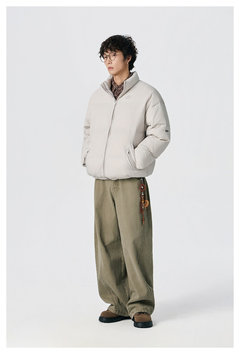 Full-length view of a model in an off-white puffer jacket and loose olive trousers.