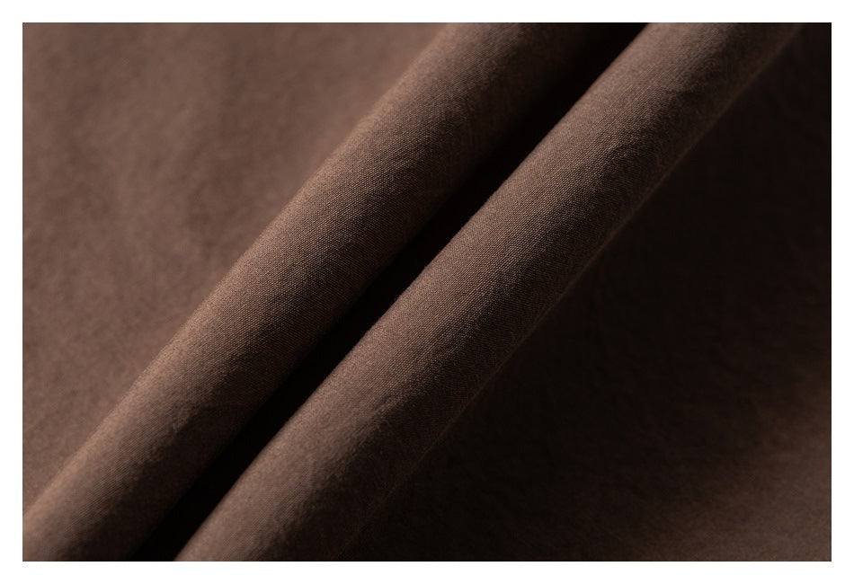 Close-up of dark brown fabric folded to show its fine surface texture.