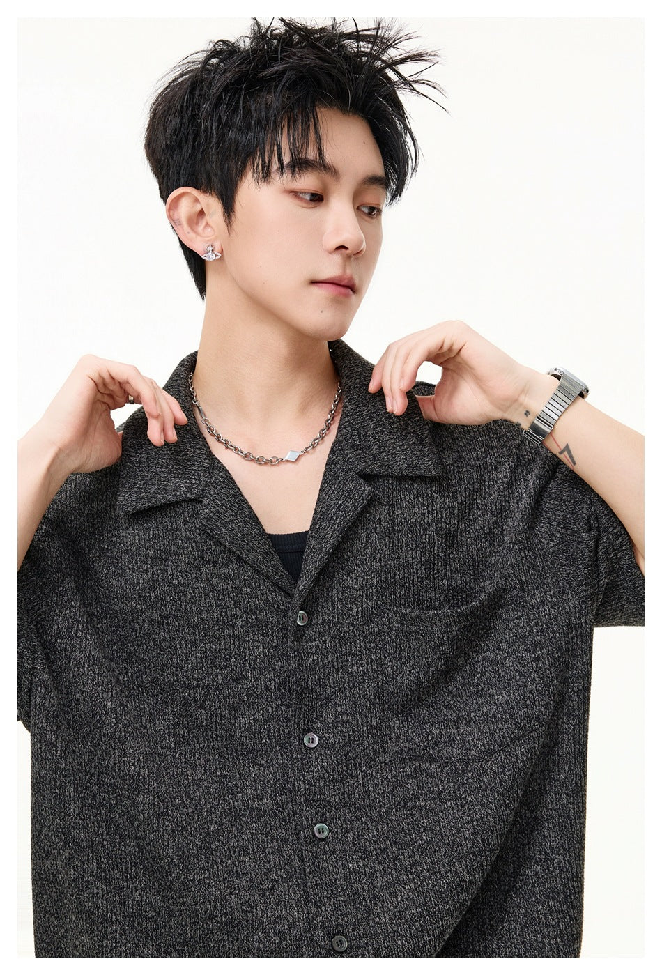 Close-up of a model wearing a charcoal gray textured button-up shirt, showing its notched collar and chest pocket.