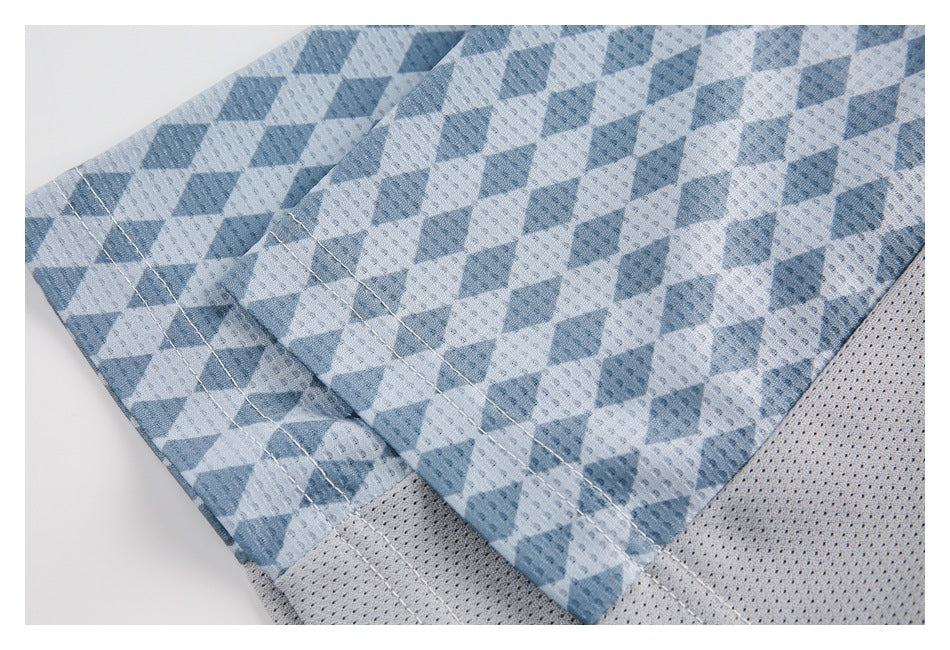 Close-up of blue geometric-print garment fabric with stitched seams and a light gray perforated mesh panel.