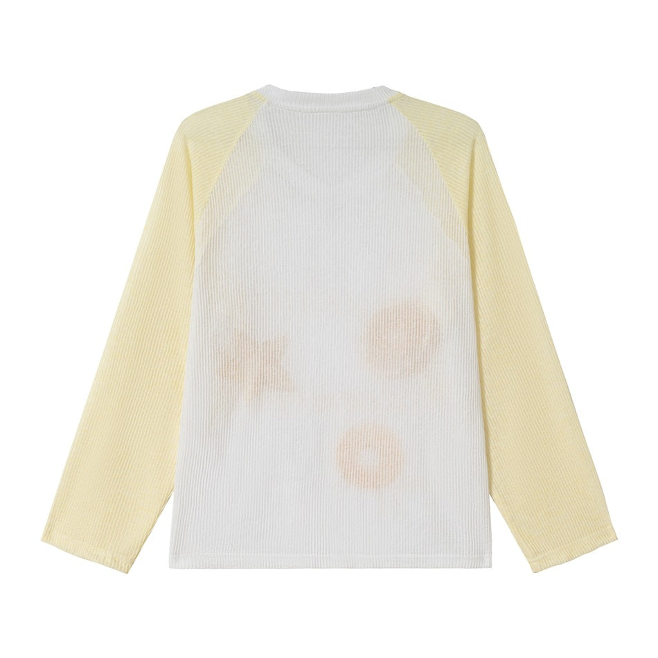 Back view of a white ribbed raglan top with pale yellow sleeves and faint fruit shapes showing through.