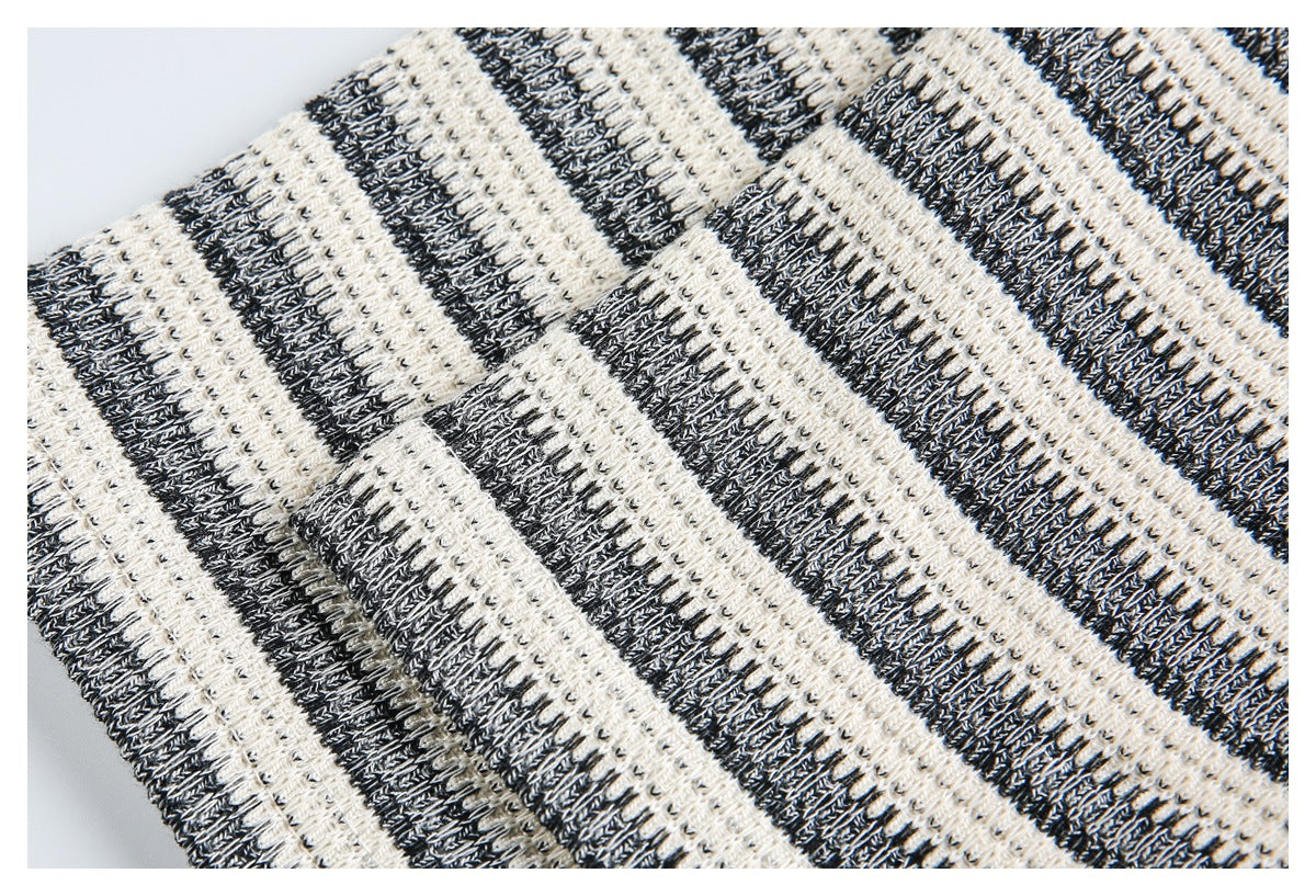 Close-up of a black and ivory striped knit garment showing its chunky textured stitches.