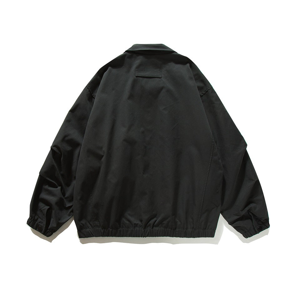 Back view of black bomber-style jacket with small horizontal flap at upper back and elastic hem and cuffs