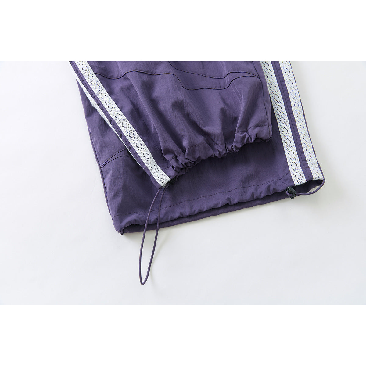 Close-up of purple pant cuffs with white lace side stripes and adjustable drawcords.
