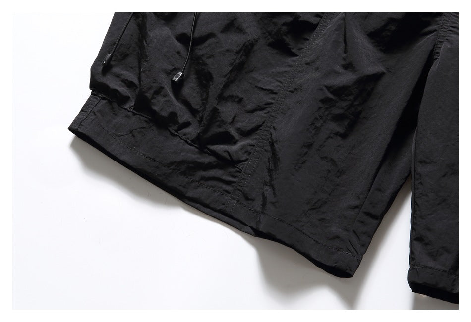 Close-up of black shorts showing a stitched leg hem and wrinkled fabric.