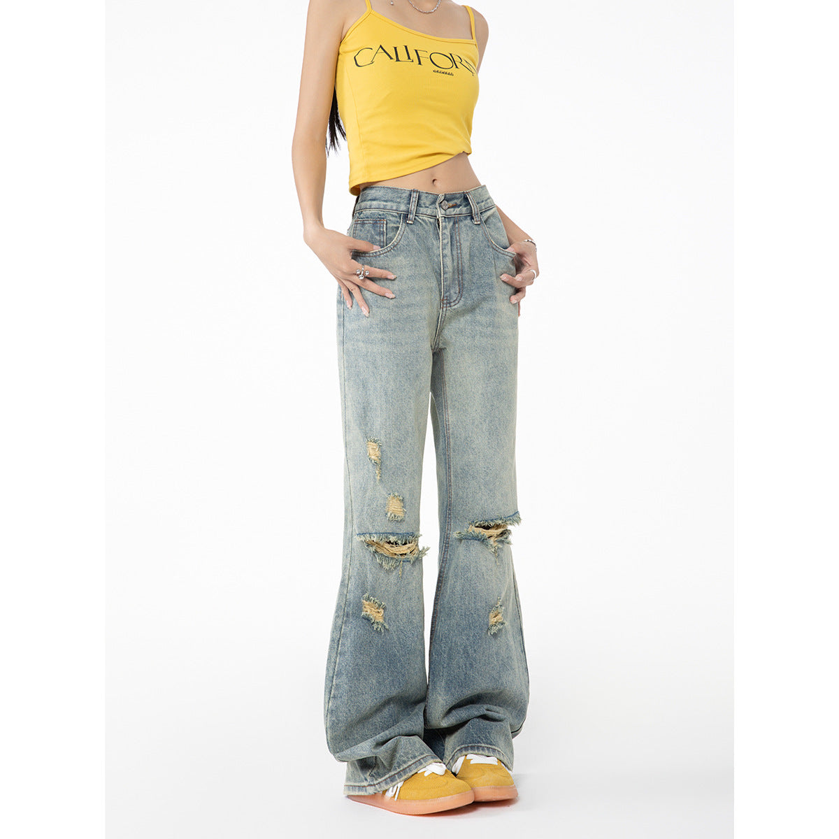 Cropped front view of a model in a yellow CALIFORNIA-print camisole and distressed light-wash wide-leg jeans.