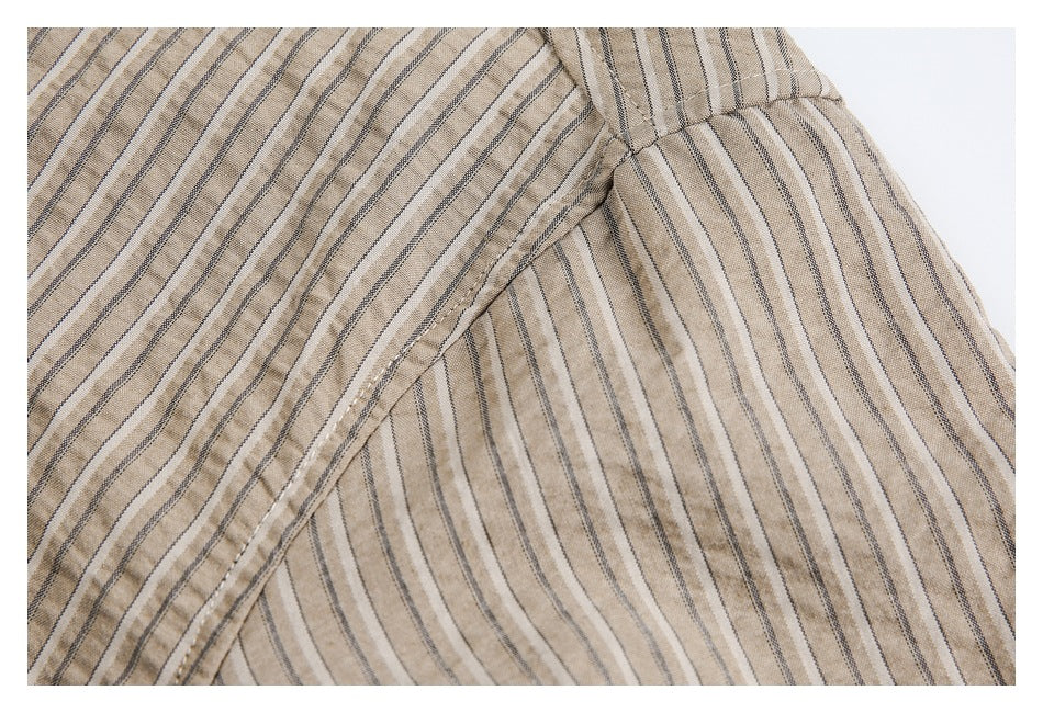 Close-up of striped tan shirt fabric meeting at a curved stitched seam.