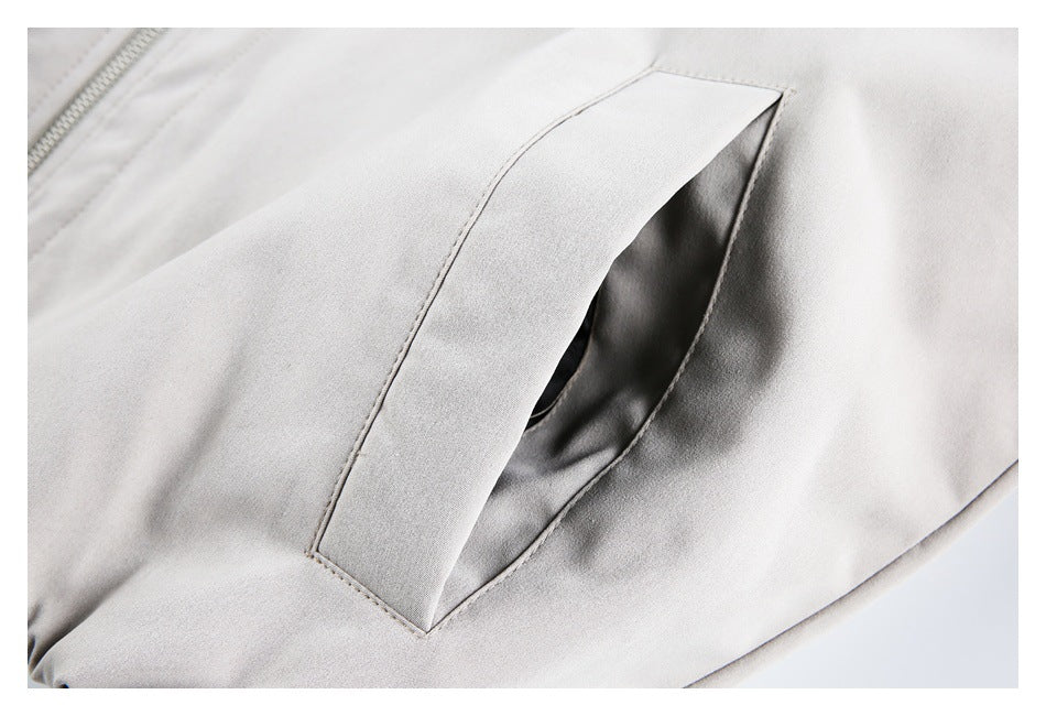 Close-up of an angled welt pocket opening on a light gray jacket.