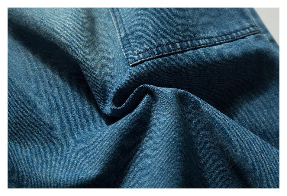 Close-up of blue denim showing a stitched pocket edge and soft folds.