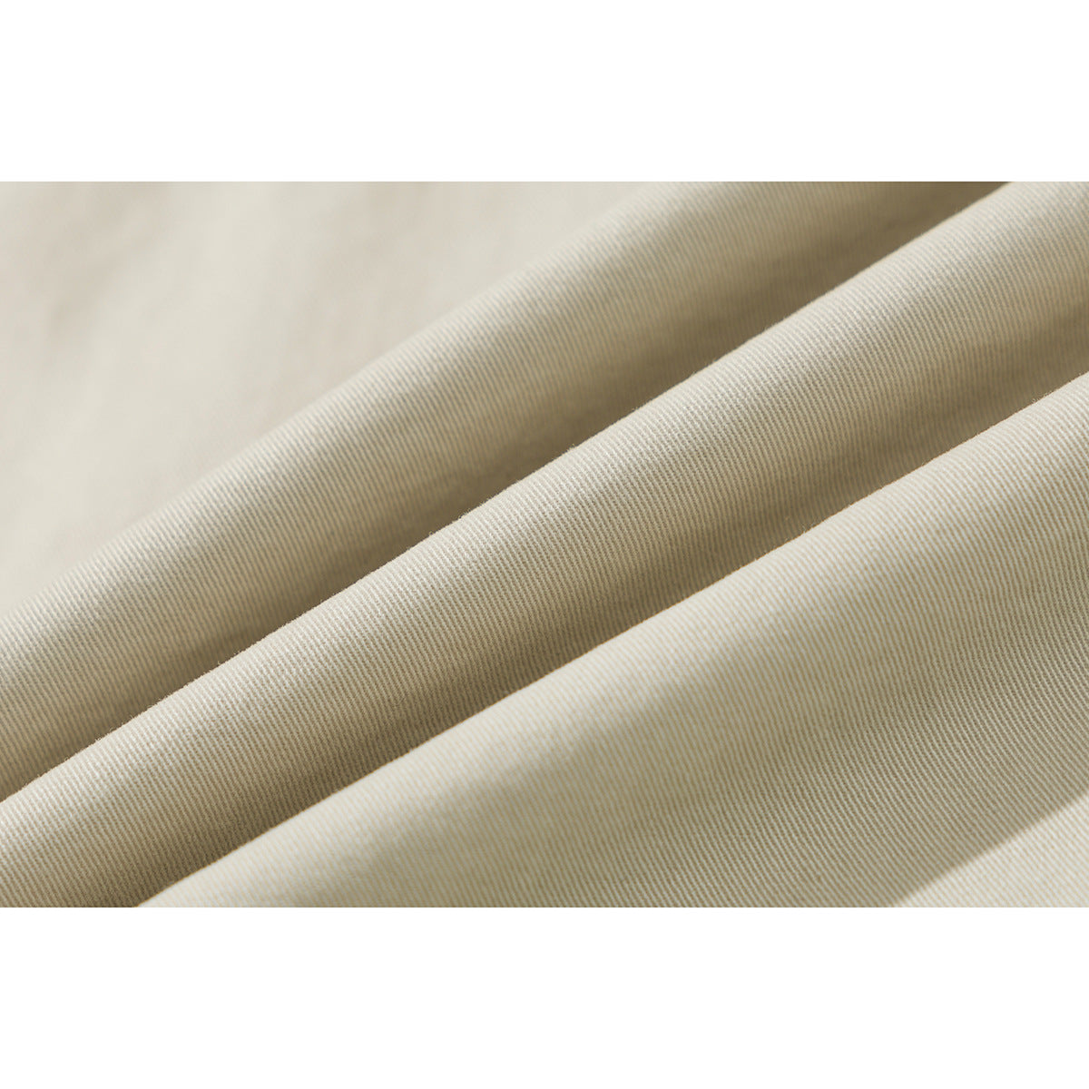Close-up of light beige fabric arranged in folds, showing its fine diagonal weave.