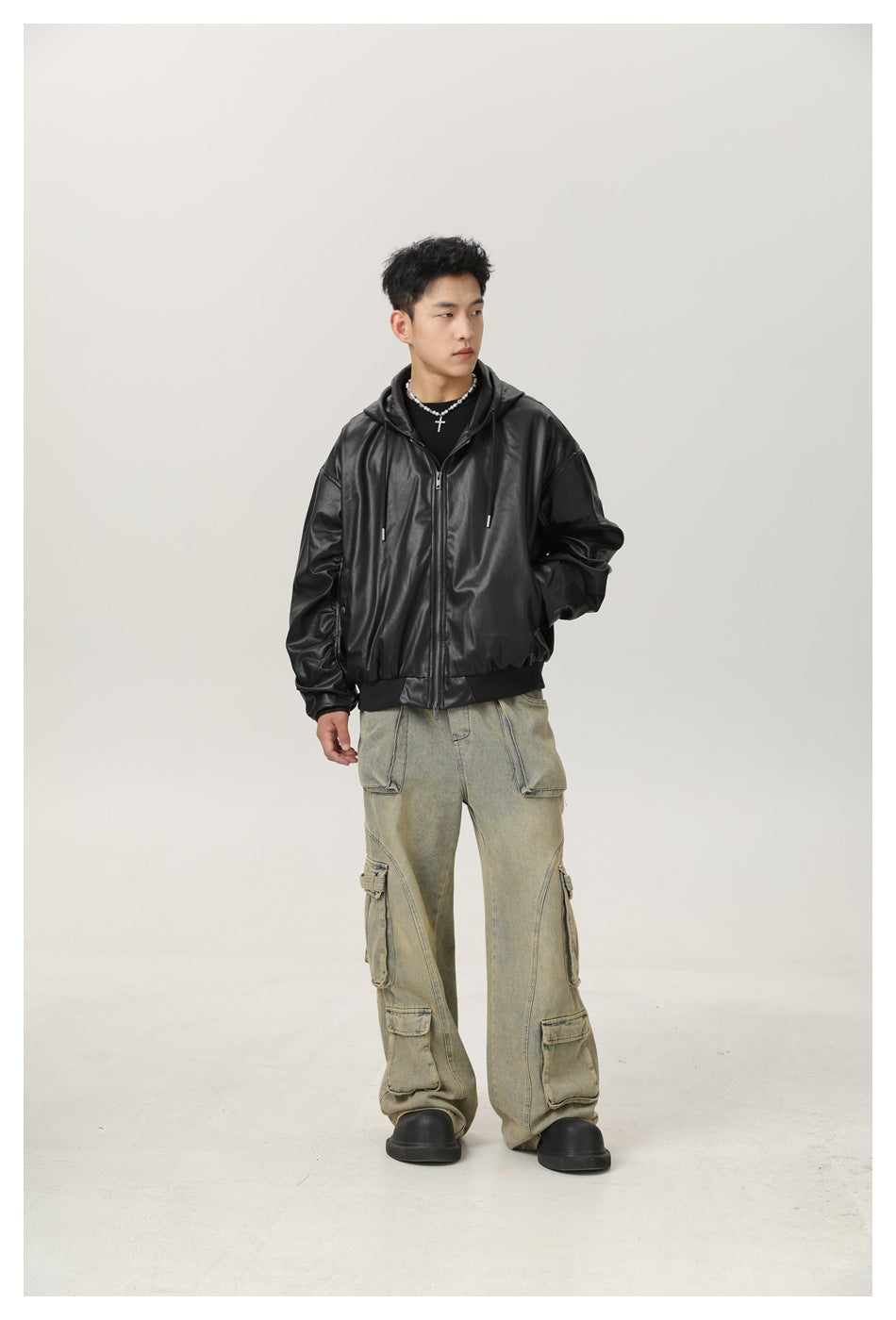 Full-length model wearing a black hooded zip jacket, faded cargo jeans, and black shoes.