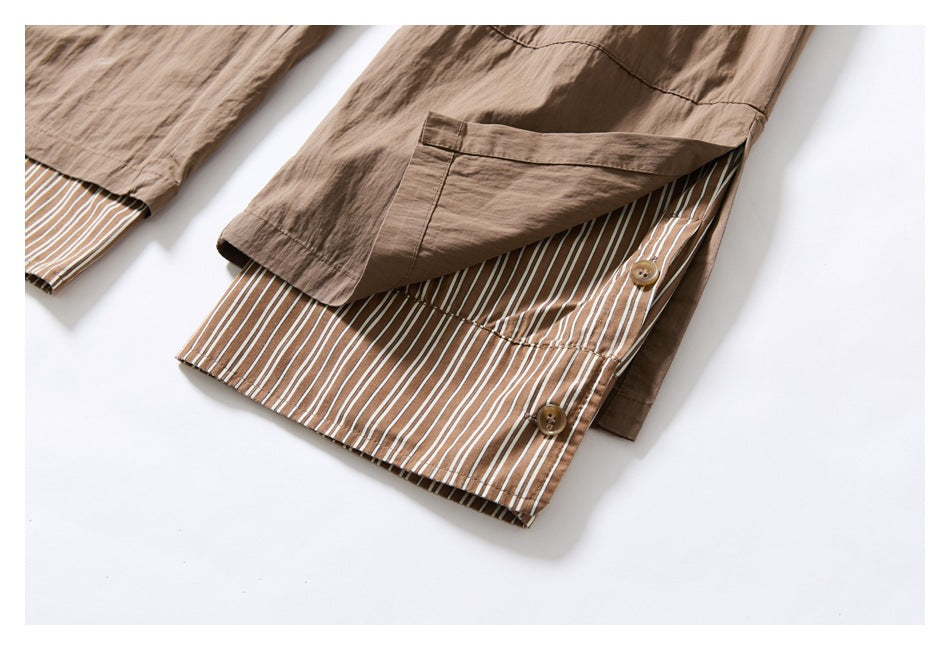 Taupe trouser leg turned up to reveal brown-and-white striped lining and two buttons at the hem.