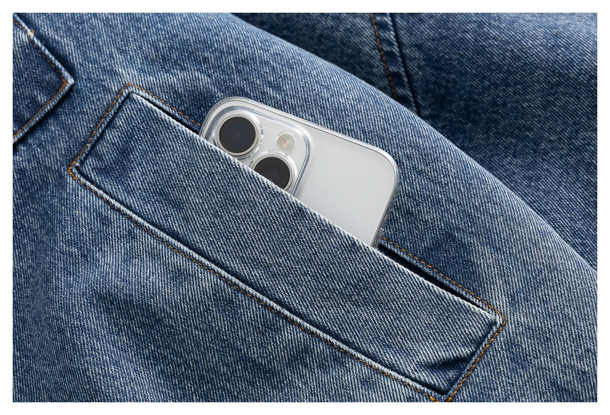Close-up of a blue denim jacket's stitched pocket holding a smartphone.