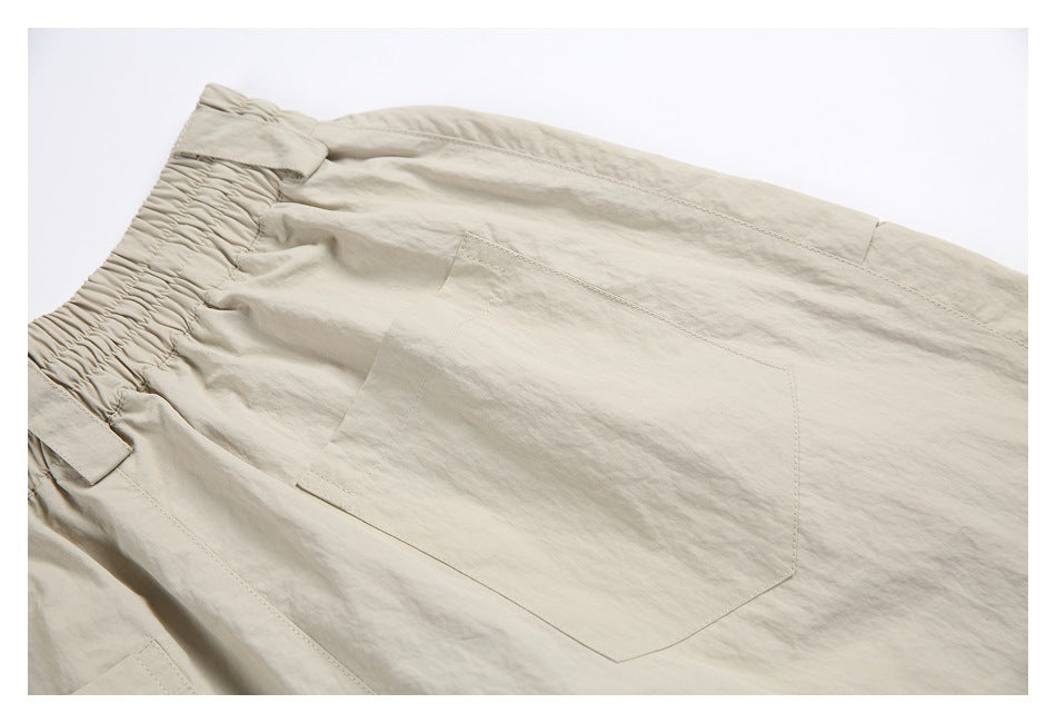 Close-up of light beige bottoms showing an elastic waistband, belt loops, and a large patch pocket.