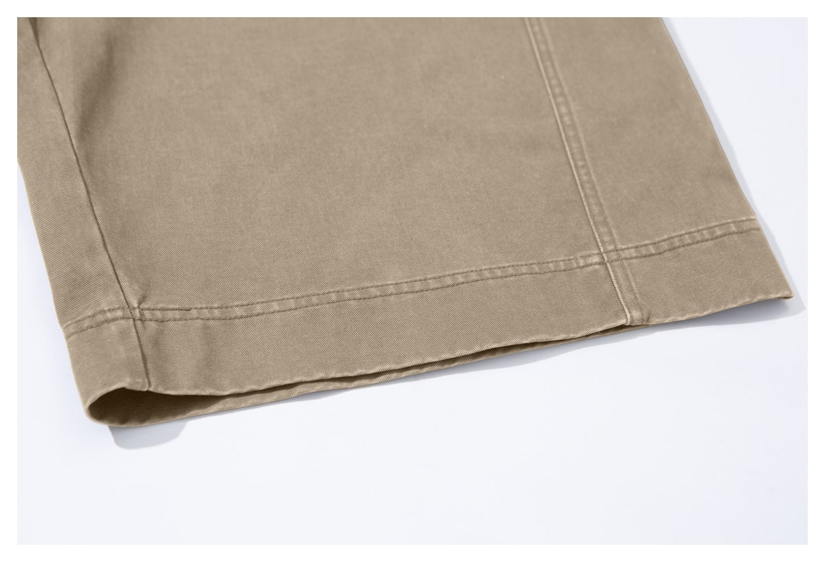 Close-up of the stitched hem and side seam on tan trousers.