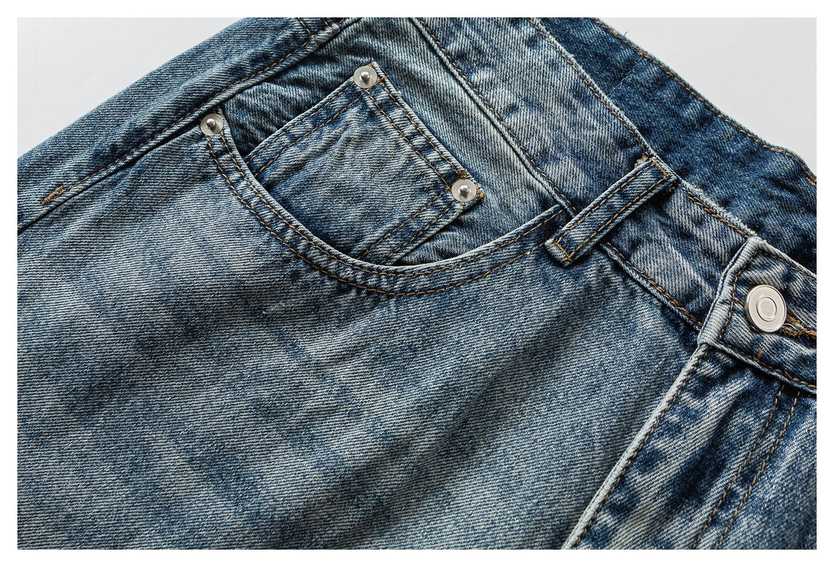 Close-up of faded blue jeans showing the small front pocket, rivets, belt loop and waistband button.