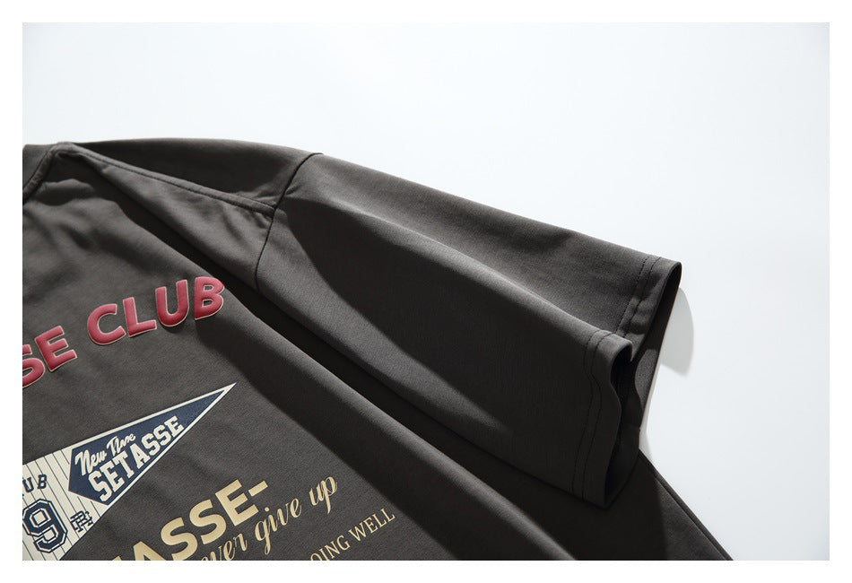 Close-up of the charcoal T-shirt's short sleeve and hem, with part of its printed back graphic visible.
