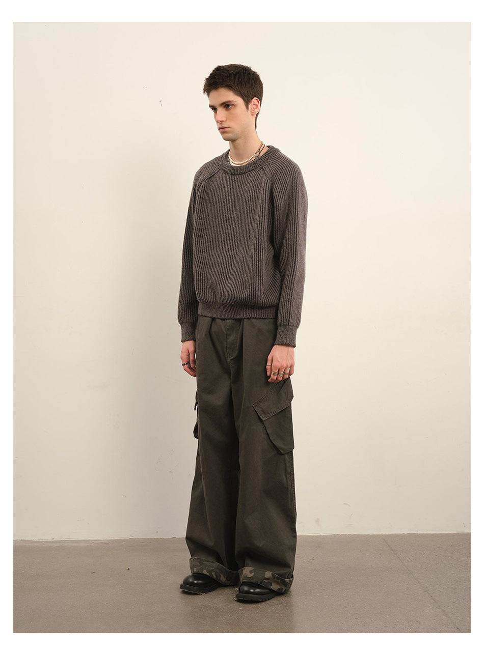 Model wearing a dark taupe ribbed crewneck sweater with raglan sleeves and olive cargo pants.