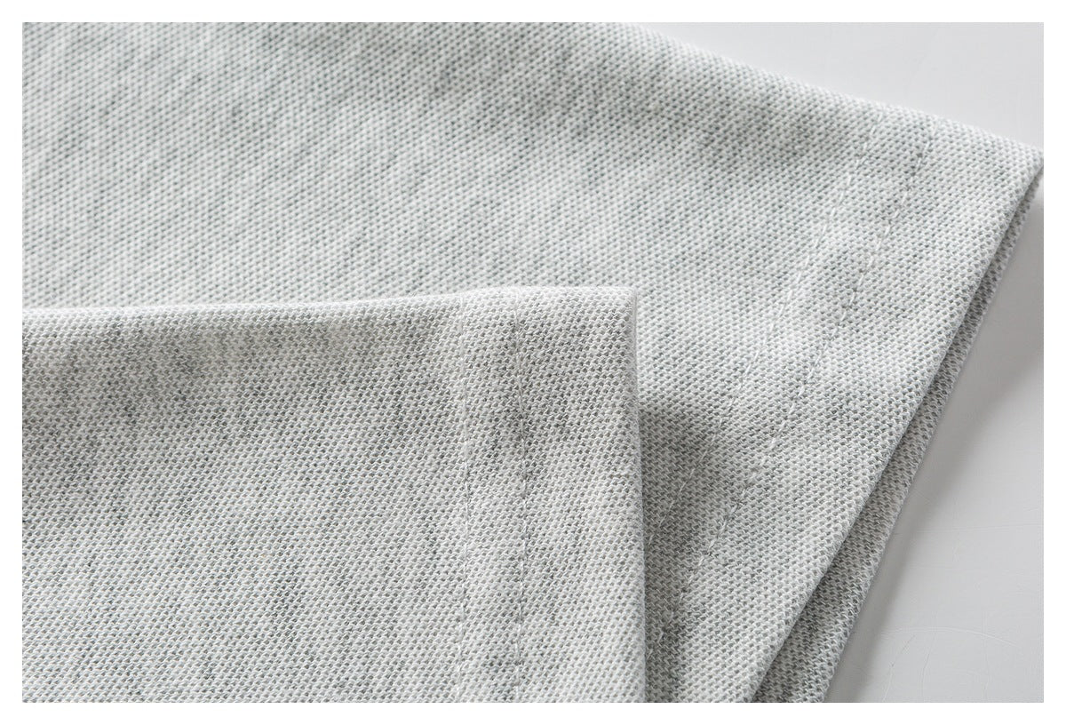Close-up of light gray knit fabric folded to show its texture and stitching.
