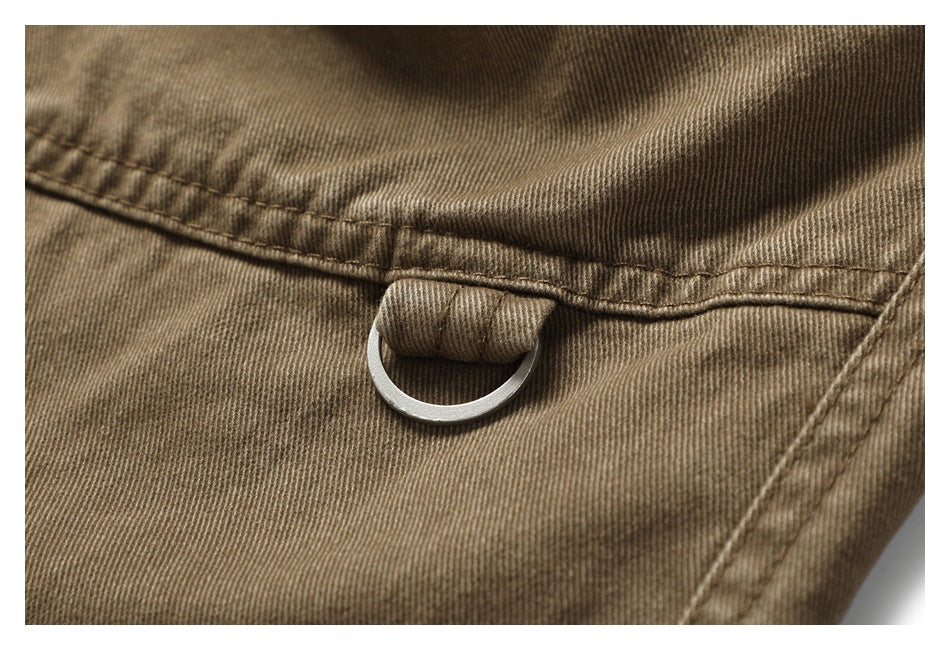 Close-up of khaki-brown trousers showing a stitched fabric loop and metal D-ring.