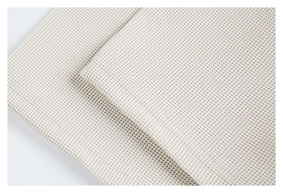 Close-up of the off-white shirt's small-grid textured fabric and a stitched seam.