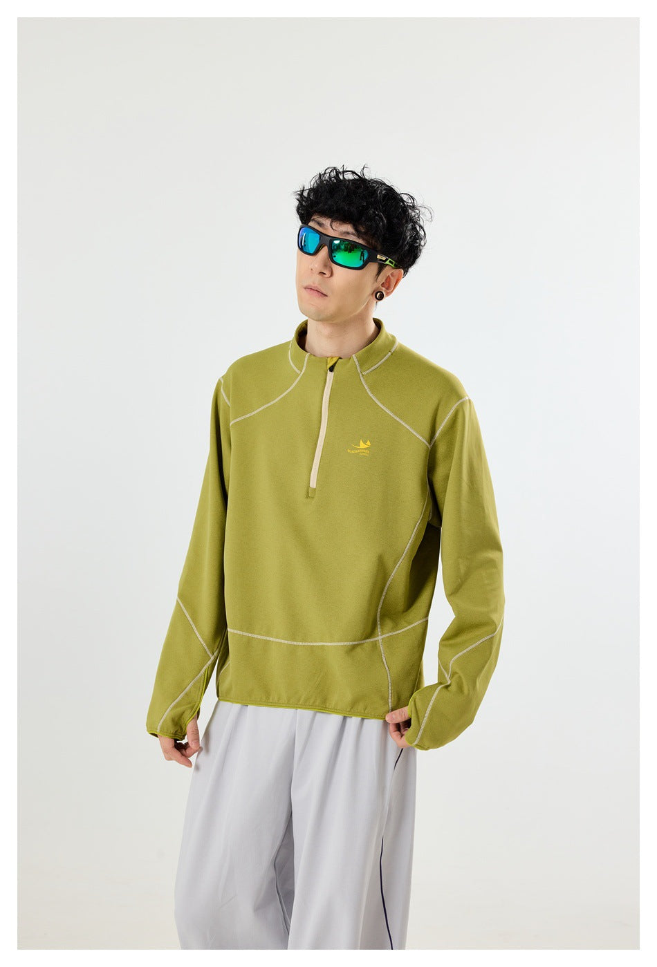 Closer view of a model wearing an olive quarter-zip pullover with contrast seam detailing.