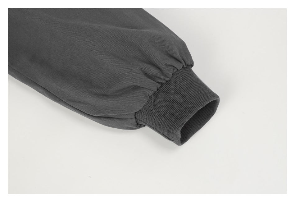 Close-up of a charcoal jacket sleeve gathered above a ribbed cuff.