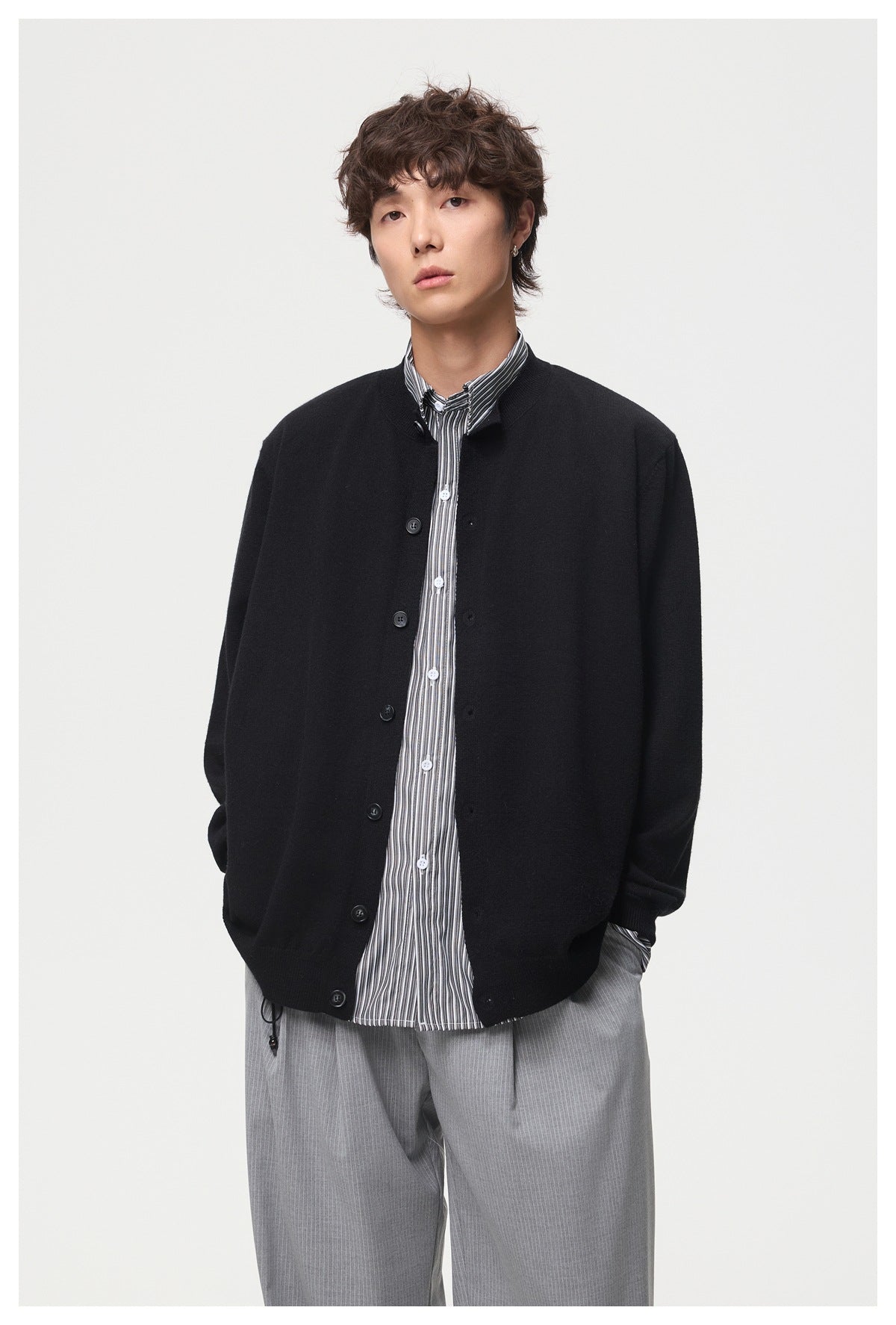 Model wearing a black button-front cardigan over a striped shirt, shown from the front.