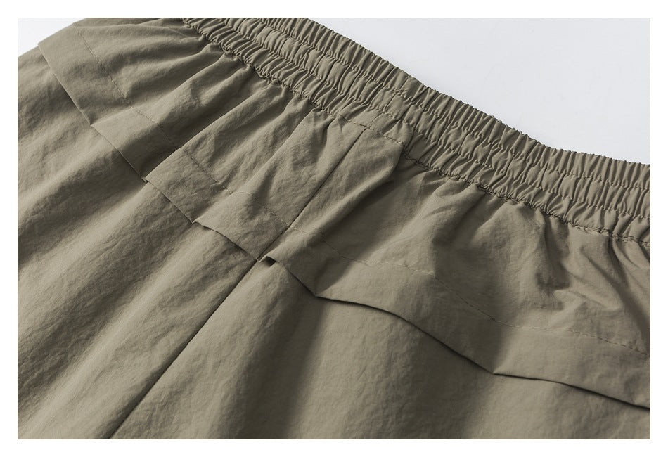Close-up of a taupe garment's gathered elastic waistband and layered stitched panels.