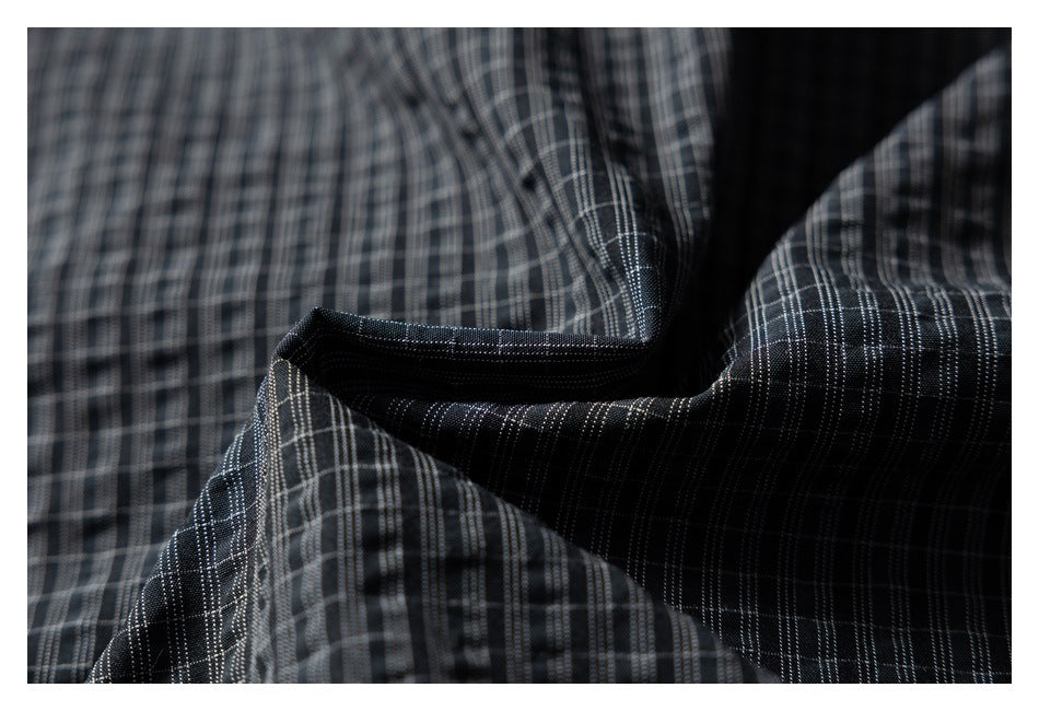 Close-up of a folded, stitched edge on dark gray plaid fabric.