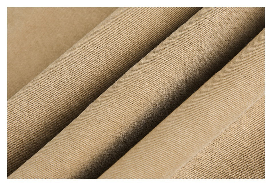 Close-up of tan pants fabric folded to show its fine diagonal weave and texture.