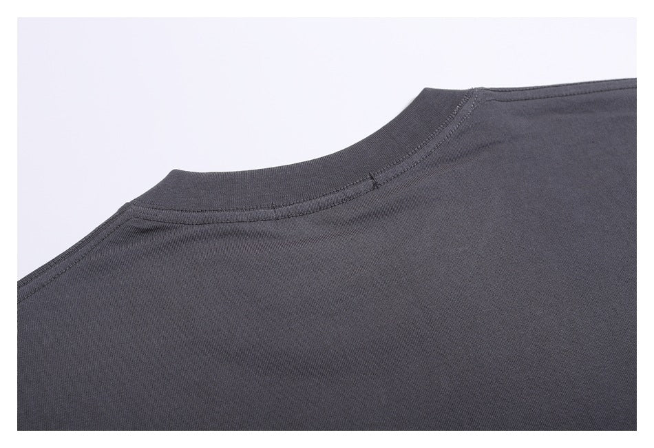 Close-up of a charcoal garment's neckline and shoulder seam against a light background.