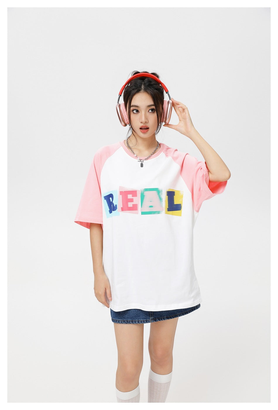 Model wearing a white raglan T-shirt with pink sleeves and colorful REAL lettering.