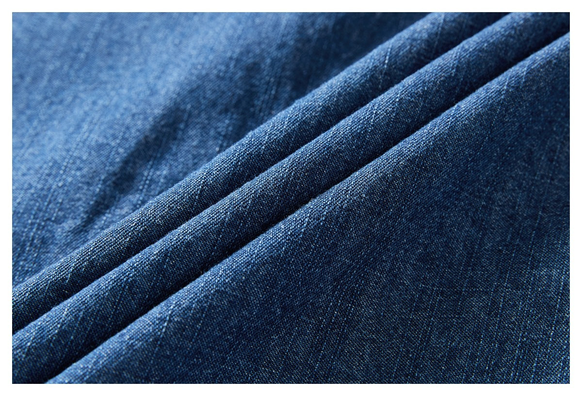 Close-up of dark blue denim fabric arranged in soft folds, showing its woven texture.