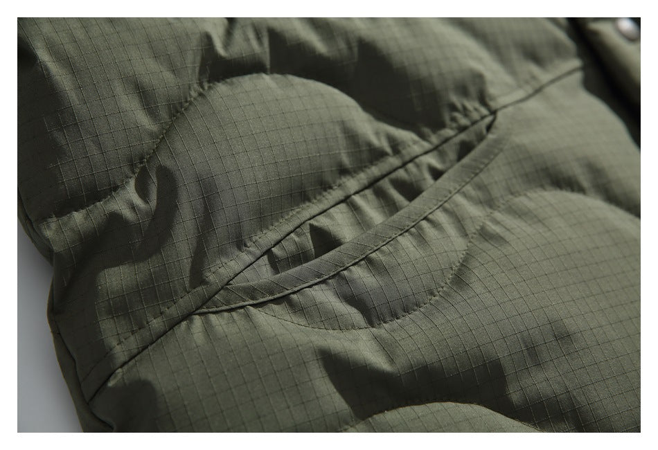 Close-up of an angled pocket seam on the olive-green quilted jacket.