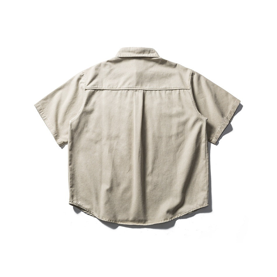 Back view of khaki short-sleeve shirt showing shoulder yoke, center pleat and curved hem