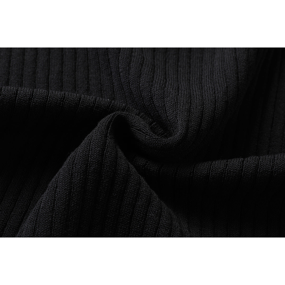 Close-up of black ribbed knit fabric gathered to show its texture and drape.