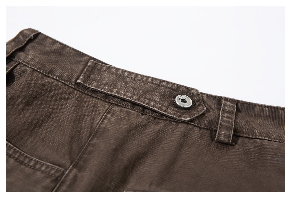 Close-up of the brown trousers' waistband, belt loops, and metal button.