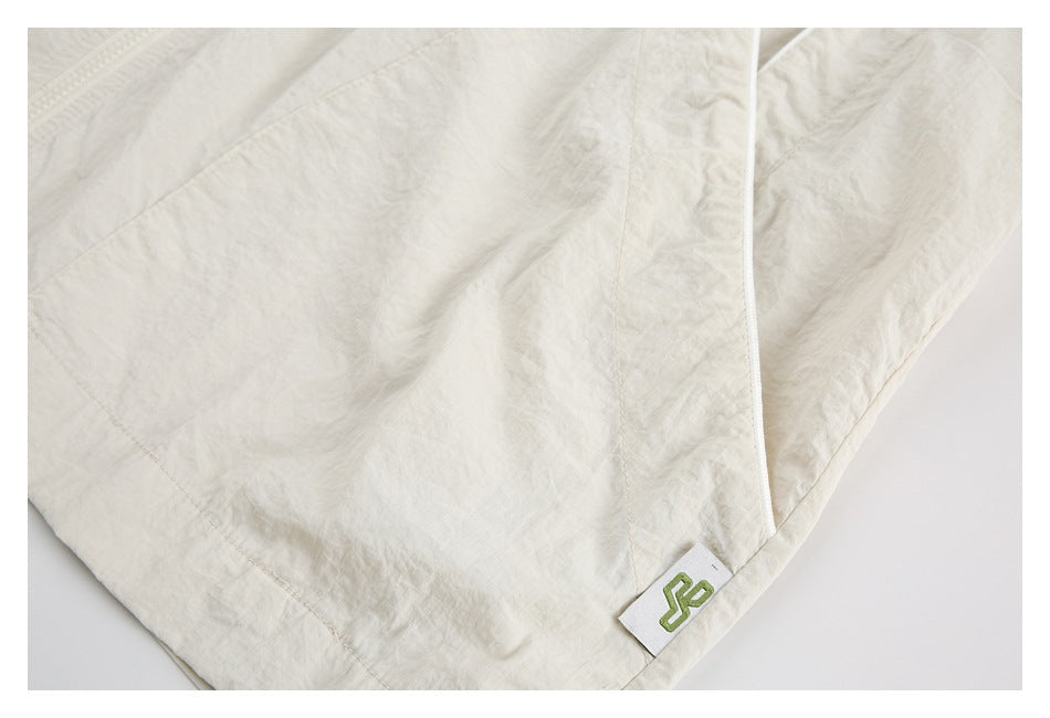 Close-up of cream fabric with curved stitching and a small white tag bearing a green emblem.