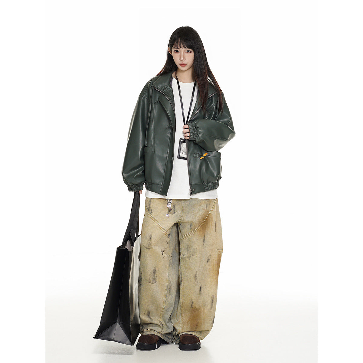 Model wearing an oversized dark green jacket with wide lapels and gathered cuffs, over a white top and loose tan jeans.