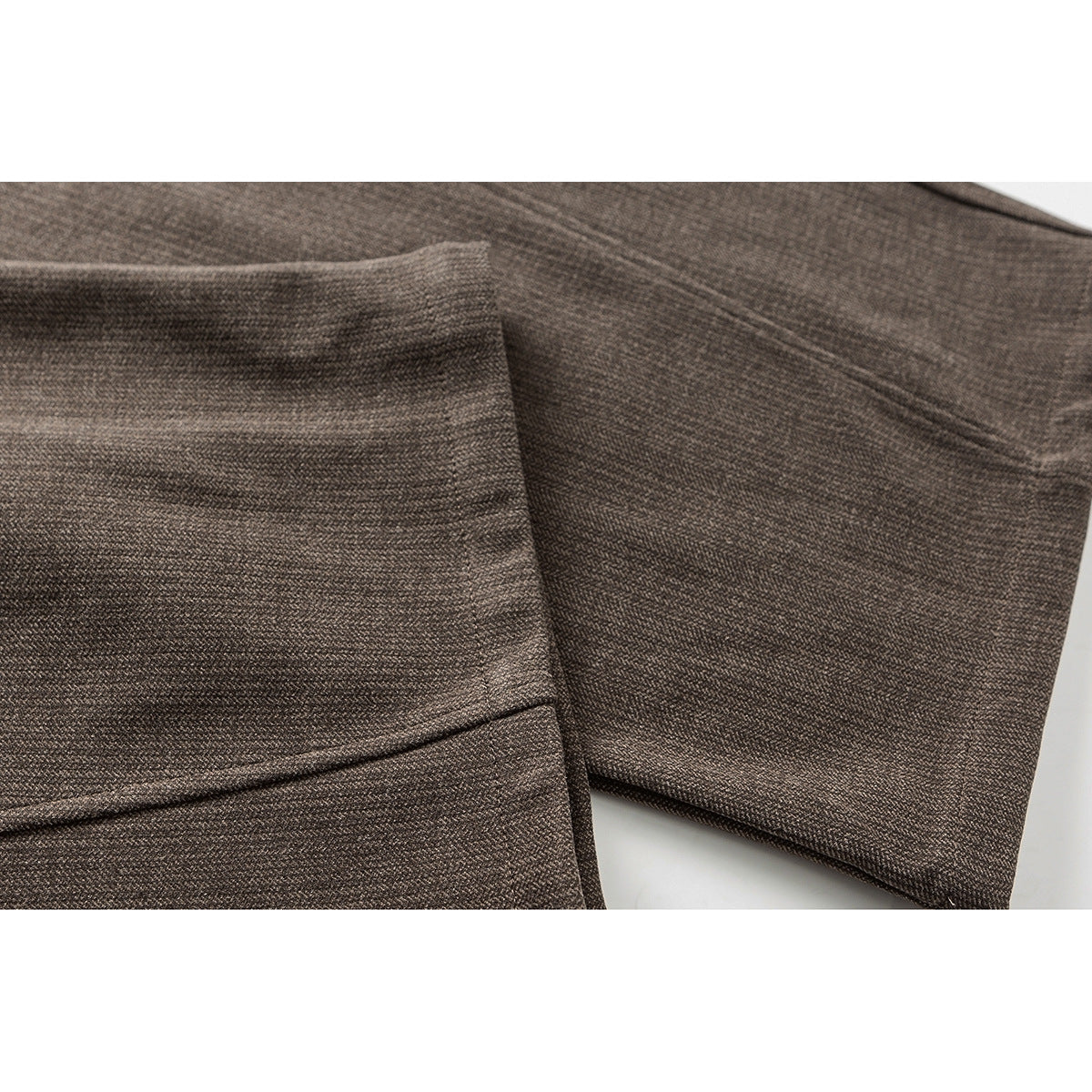Close-up of brown trousers showing a stitched pocket and wide leg hem.