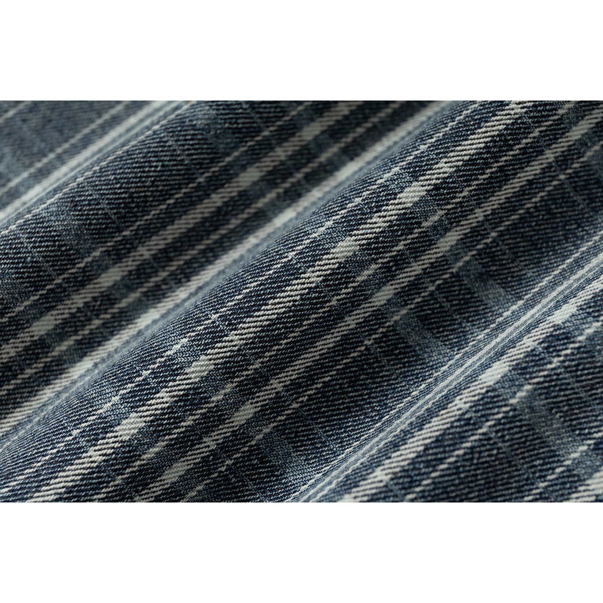 Macro view of blue-gray plaid fabric with intersecting cream stripes.