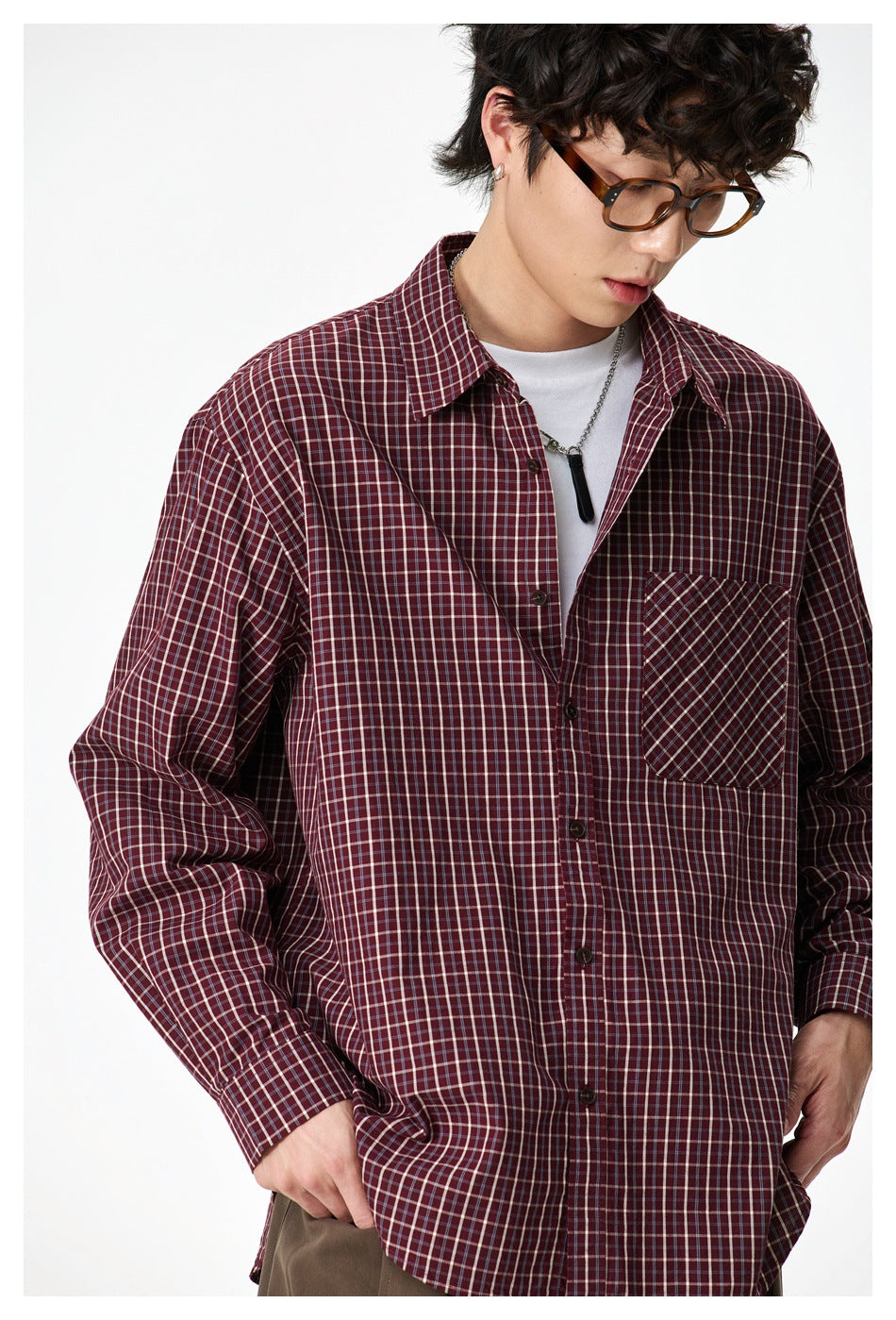 Close-up of a model wearing a burgundy plaid button-up shirt with a diagonally patterned chest pocket.
