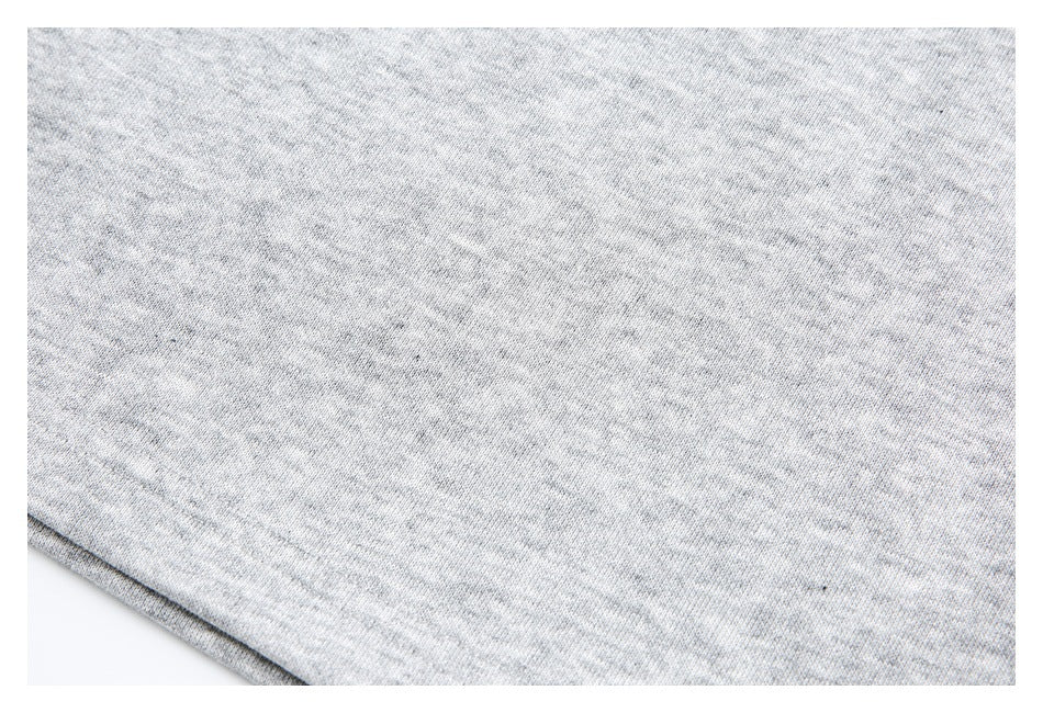 Close-up of light gray heathered fabric and a stitched garment edge.