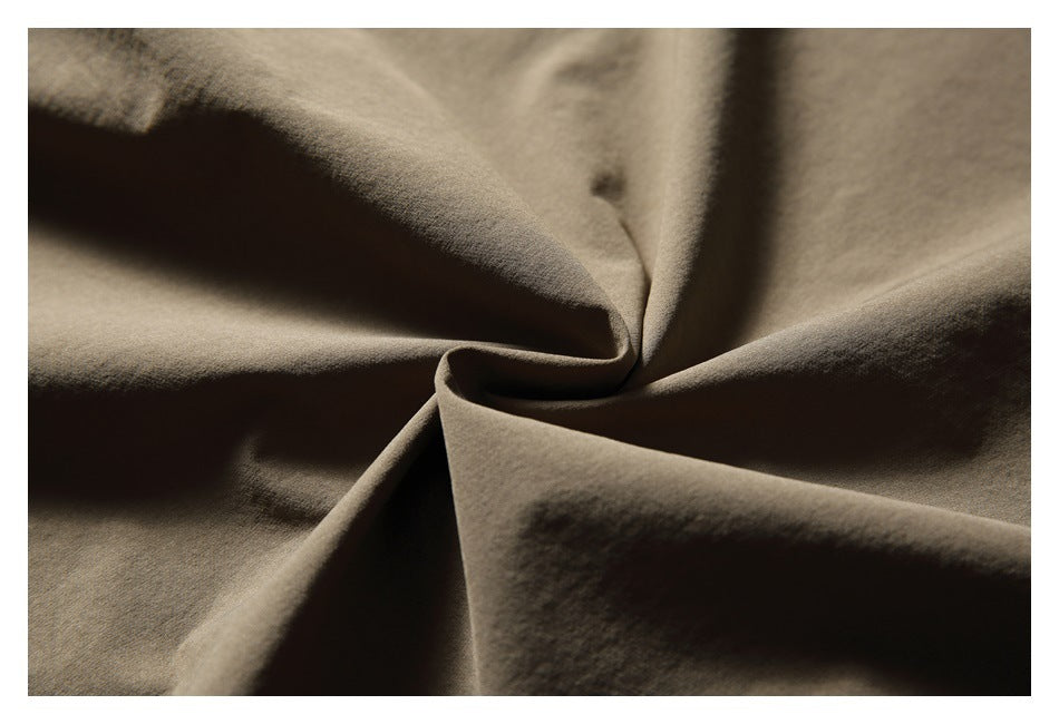 Close-up of taupe-brown fabric draped into soft folds, showing its surface texture.
