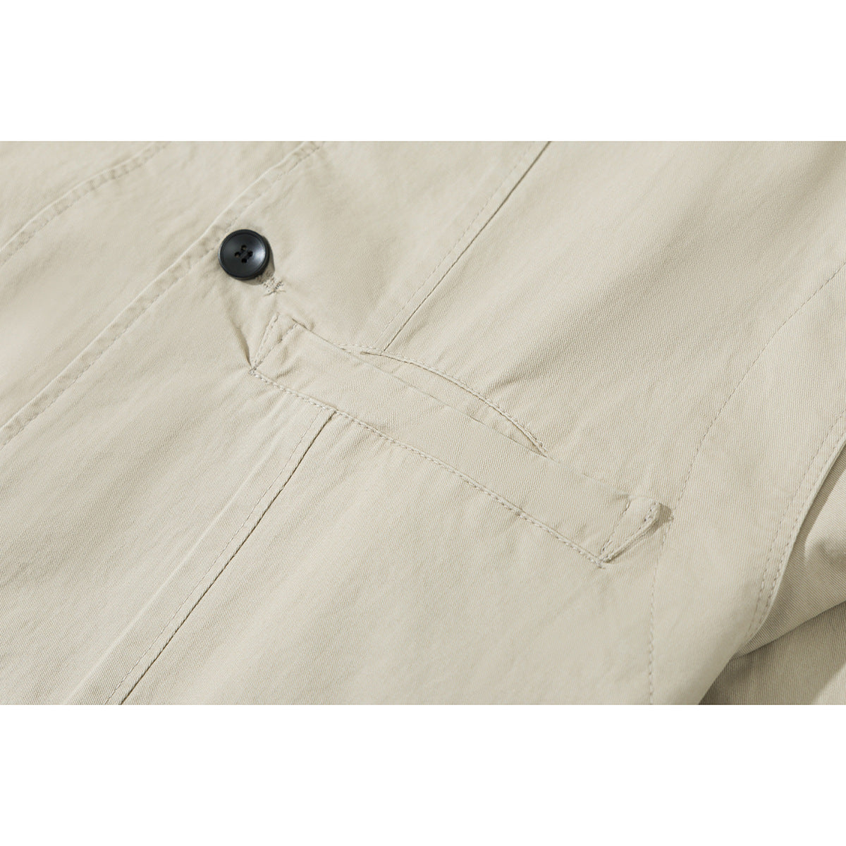 Close-up of a light beige jacket's black button, stitching, and angled front pocket.