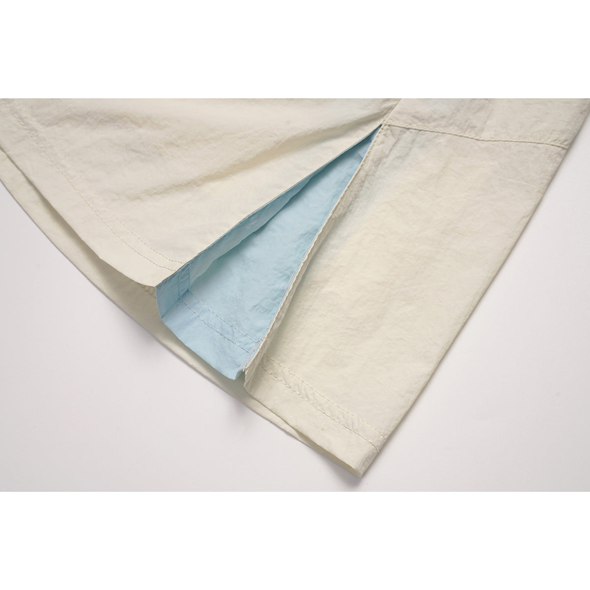 Close-up of an ivory skirt's side slit, showing the light-blue inner panel and hem stitching.